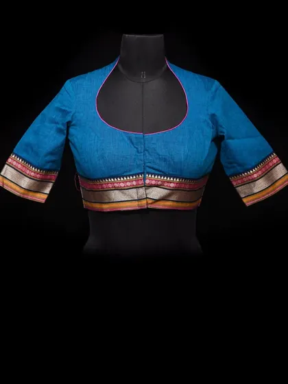 A studio shot of our blue blouse with a unique cut and contrasting border detail on the sleeves.