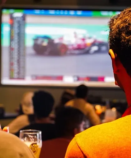 Two friends completely engrossed in the F1 race, with a cold beer in hand. It's the perfect way to experience the thrill of the track.