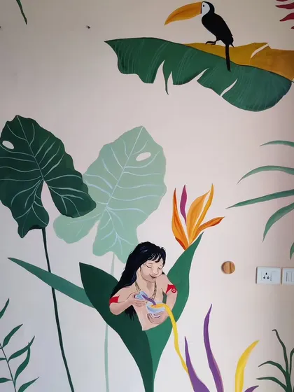 A close-up of another character from the Poldi mural, peeking out from behind a large leaf, with a toucan perched above.