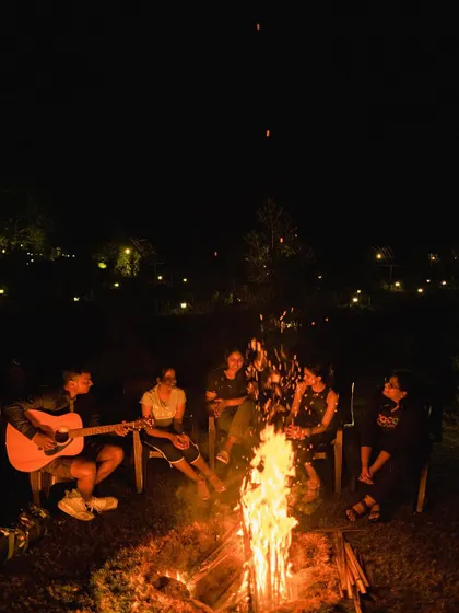 A classic campfire scene. A team gathers around the warm fire, enjoying music and conversation. This is the heart of the camping experience and a fantastic way to foster connections.