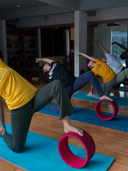 Students in a side-angle pose with one foot on a yoga wheel, adding a balance challenge to the classic asana.