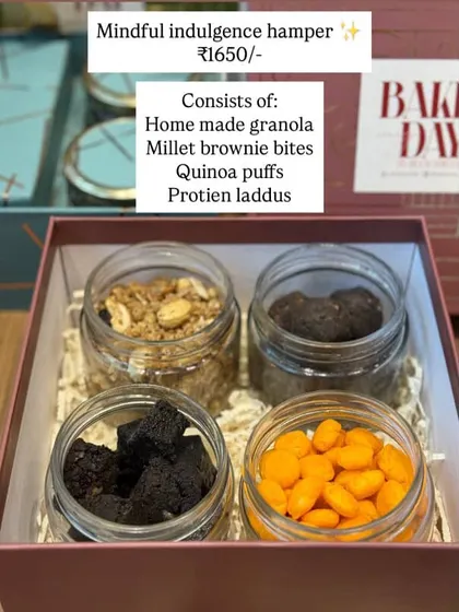 The Mindful Indulgence Hamper menu. A healthy and delicious option consisting of homemade granola, millet brownie bites, quinoa puffs, and protein laddoos.