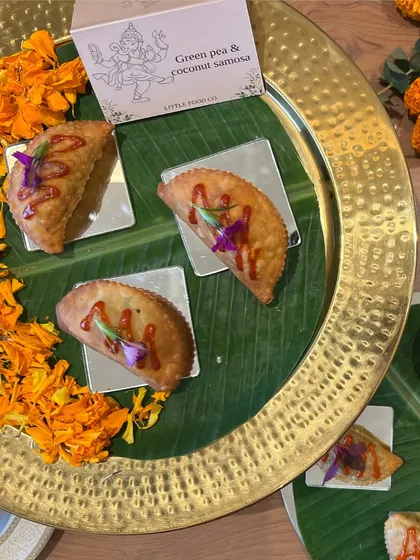 Our Green Pea and Coconut Samosas, served on a banana leaf with floral decorations. This was another special item from the festive menu we created for Virat and Anushka's Ganpati celebration.