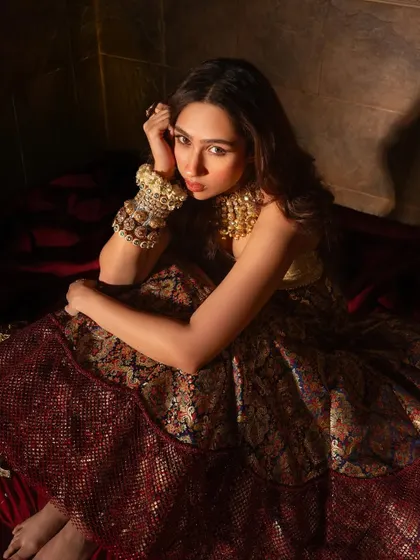 A moody and artistic shot of Pashmina Roshan, her thoughtful pose highlighting the intricate details of her gold jewelry.