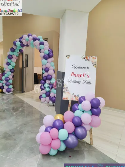 A welcome area for Aanvi's birthday party, featuring a personalized sign on an easel and a lovely pastel balloon arrangement.