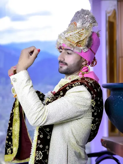 A candid shot of the groom getting ready, adjusting his attire with the mountains visible in the background.