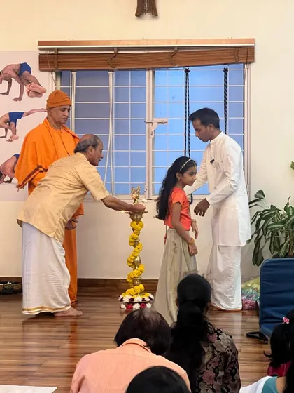 The next generation also participates in our traditions. Here, a young student joins in lighting the lamp. It is important to involve children in these rituals to instill in them a deep-rooted connection to our culture and spiritual path.
