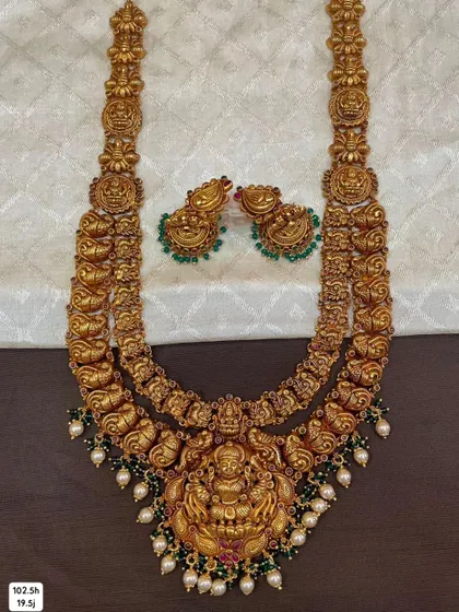 This is a layered bridal necklace set made from hallmarked 92.5 silver with gold plating. It comes with matching jhumkis and is adorned with green beads.