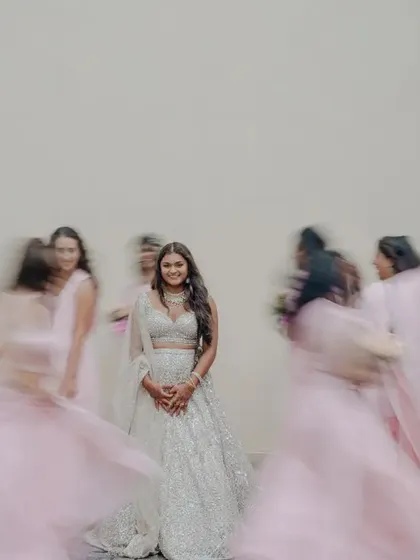 A creative portrait of the bride with her bridesmaids, using motion blur to create a dynamic and artistic effect. The bride stands still and serene amidst the joyful chaos of her friends.