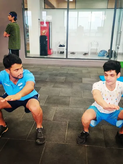 Our head coach demonstrates proper squat form alongside a young athlete. Functional fitness is a critical part of our curriculum to improve stability and endurance.