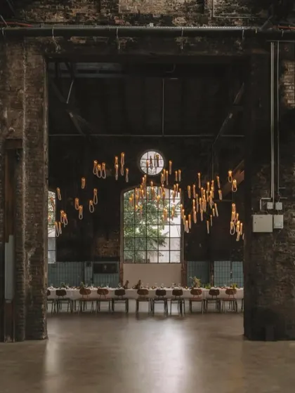 An atmospheric shot of the Bocci 87 installation in a vast, raw space. The warm light from the looped pendants creates a sense of intimacy and grandeur simultaneously.