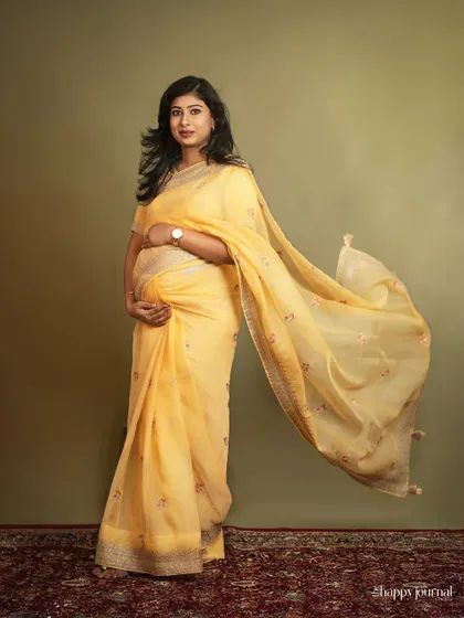 Wrapped in sunshine and love. A flowing yellow saree brings a radiant glow to this maternity portrait, celebrating the beauty and strength of motherhood in every elegant drape.