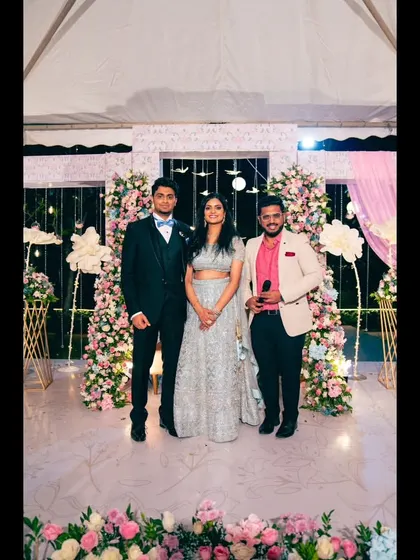 Standing with the couple on their beautifully decorated Sangeet stage. I'm here to ensure the event flows smoothly and everyone has a gala time.