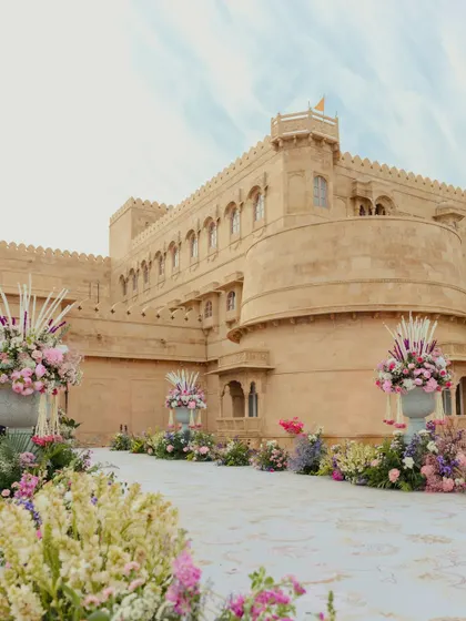 The grand aisle leading to the Suryagarh palace entrance, lined with massive urns of pastel flowers, setting a majestic and romantic tone for the wedding.