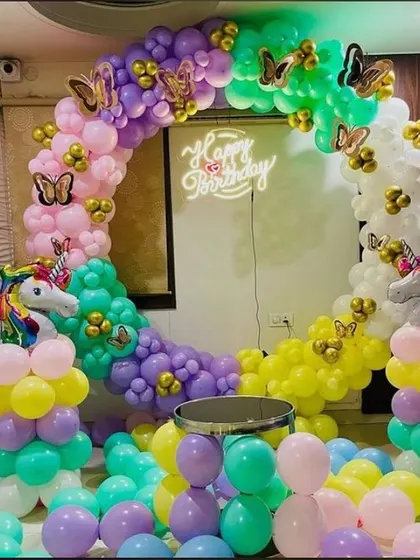 A closer look at the rainbow unicorn and butterfly decoration. The circular balloon arch is filled with bright colors and accented with gold butterflies, creating a fun and vibrant photo corner.