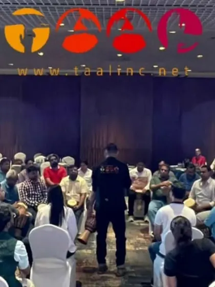 A wide shot of a corporate drum circle in full swing. You can see the focus and engagement as the facilitator guides the group towards finding a common beat, a powerful tool for building a cohesive team.