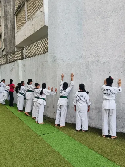 Students line up against the wall for conditioning drills. This builds endurance and discipline, teaching them to be comfortable with being uncomfortable.