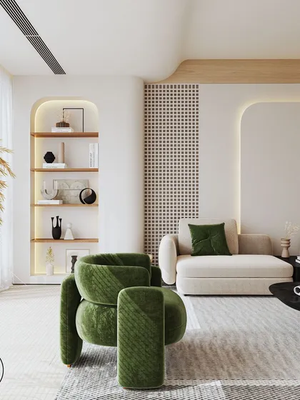 This shot showcases a cozy corner with a built-in arched bookshelf and a comfortable chaise lounge. The combination of a sculptural green armchair and a large vase of pampas grass adds layers of texture and personality.