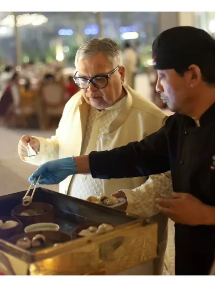 A guest being served piping hot dim sum by our chef at a live Pan-Asian counter during a Mehendi ceremony.