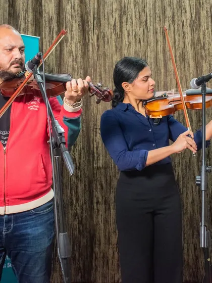 A photo of a violin duo, a teacher and student, performing together at the HSR open mic.