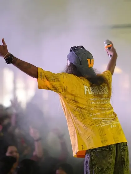 Arms outstretched, embracing the energy of the crowd at a packed college auditorium.