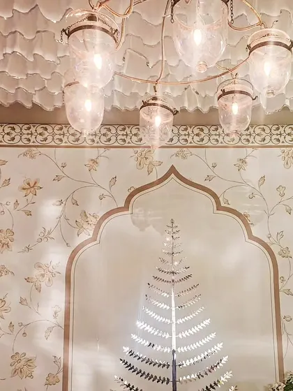 A view looking up at the elegant glass chandelier and the custom wallpapered backdrop. The design is a study in sophisticated patterns and textures.