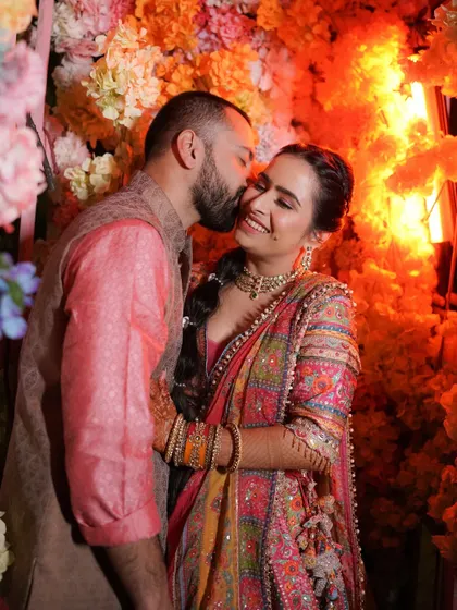 A sweet kiss on the cheek against a backdrop of vibrant flowers. This candid shot is full of warmth, happiness, and affection.