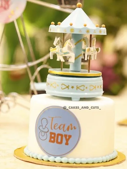 A close-up of the "Team Boy" mini cake with a blue carousel topper, part of a larger dessert table.