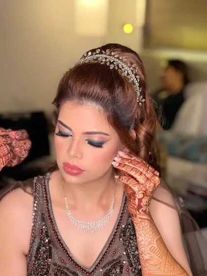 The final touches being put in place. The high ponytail and dramatic eyes create a very chic and modern party look.