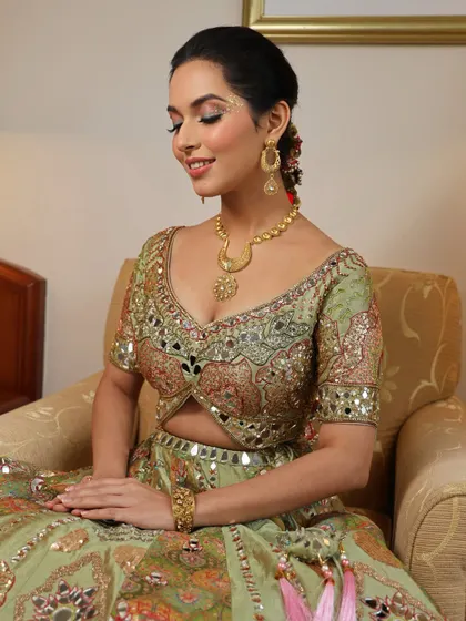 The complete picture of a happy Mehendi bride. The soft, glowing makeup and elegant updo perfectly complement her ornate green lehenga, creating a look of pure joy.