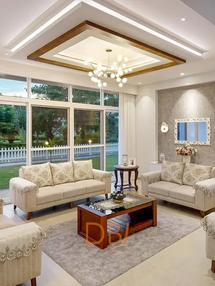 A bright and welcoming living room with large windows that look out onto a green garden. The classic sofa arrangement and warm, neutral tones create a comfortable yet elegant space, perfect for family gatherings.