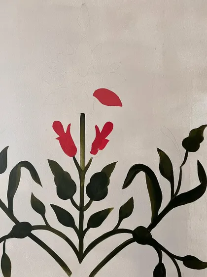 The beginning of a Mughal motif, with the first red petals being painted. This shows the careful, piece-by-piece construction of the intricate design.
