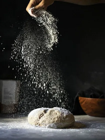 A dramatic shot of flour being dusted over fresh dough.