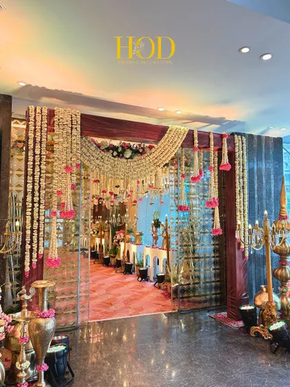 This entrance is a perfect blend of tradition and elegance, with heavy garlands of jasmine and pops of pink flowers. The design guides the eye through the doorway to the beautifully decorated space within, creating a warm and inviting welcome.