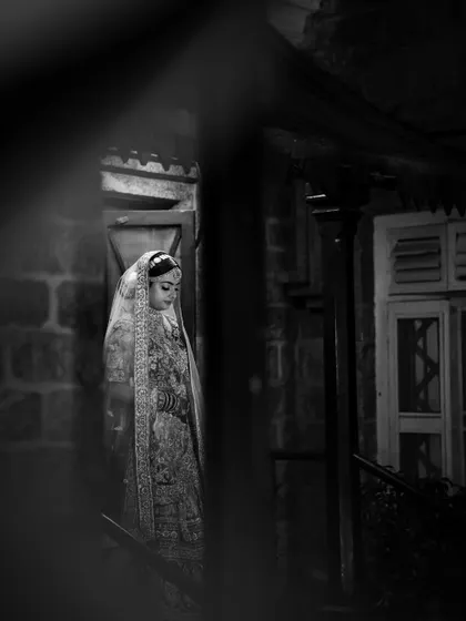 Peeking through a doorway to capture a candid moment. This black and white shot feels intimate and timeless, a quiet portrait of the bride in her own world before the ceremony begins.