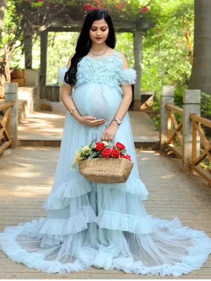A solo shot of our light blue ruffled gown on a picturesque bridge. The dress's long train and delicate details make it a perfect centerpiece for your maternity photos.