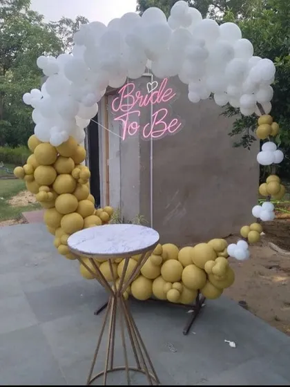 A modern and minimalist "Bride to be" backdrop. This design features a C-shaped balloon arch in mustard yellow and white on a circular frame, paired with a sleek cake stand for the celebration.