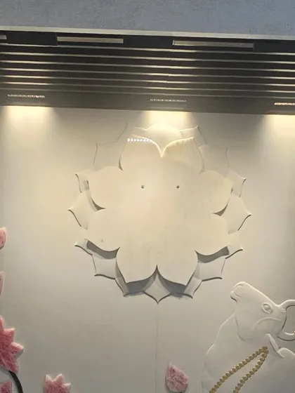 A spiritual-themed mural featuring a lotus and Nandi, carved in stone with delicate coloring. We specialize in creating custom pieces for sacred spaces.