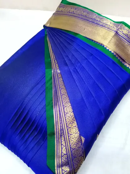 A royal blue saree with a green and gold border. It's pre-pleated and box-folded, making it convenient to store and easy to wear.