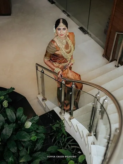 A stunning portrait of the bride descending a modern staircase, her traditional attire looking regal and elegant.