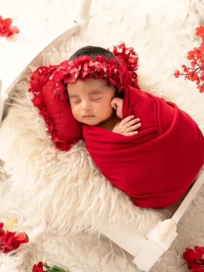 An overhead view of the baby in the red wrap, sleeping soundly on a fluffy white blanket.