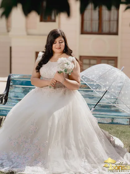 A solo portrait of the bride, looking serene and beautiful with her bouquet and umbrella. This shot highlights her elegance against the backdrop of the estate.