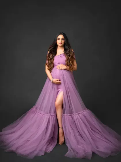 This full-length studio portrait features a lavender tulle gown with a thigh-high slit and a sweeping train. It's a modern and stylish choice for your maternity photoshoot.