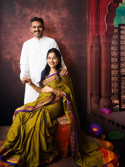 This classic couple pose captures the elegance of traditional attire. The rich olive green saree and simple white kurta create a beautiful contrast against the artistic backdrop.