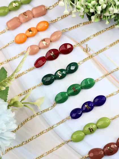 A lineup of our semi-precious stone Rakhis, showing the variety of colors and the custom initials on each.