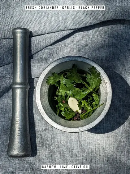 The simple, powerful ingredients for our coriander pesto: fresh coriander, garlic, black pepper, cashew, lime, and olive oil.