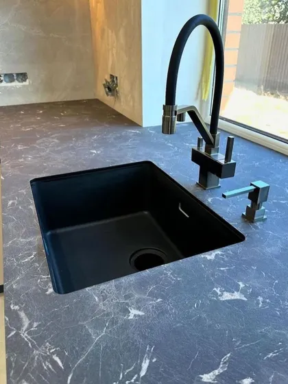 We pay attention to every detail, including the sink and faucet. This kitchen features a modern black sink and a flexible faucet, seamlessly integrated into the dark marble-finish countertop.
