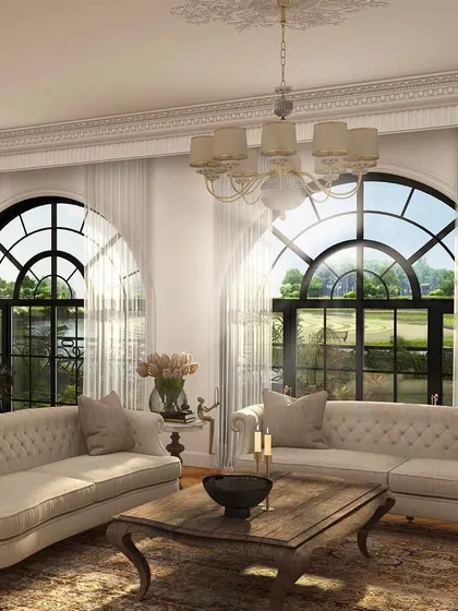 An intimate living space featuring classic Chesterfield sofas and arched windows that flood the room with light. The design creates a comfortable yet formal setting, perfect for conversation and entertaining.