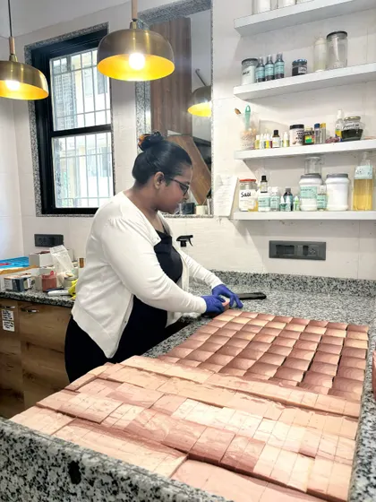Here I am cutting a large loaf of soap into individual bars using our multi-bar cutter. This tool helps us ensure every bar is uniform in size.
