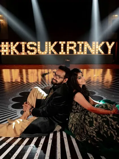 The couple poses with their custom marquee hashtag sign, a popular feature for modern Sangeet nights.